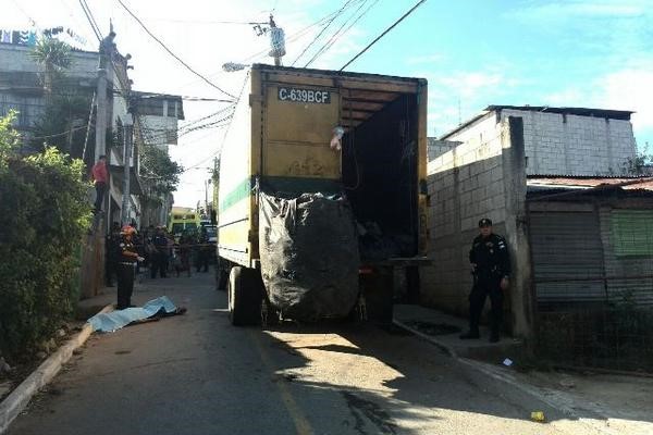 Camión recolector de basura, bomberos y policía junto a persona fallecida.