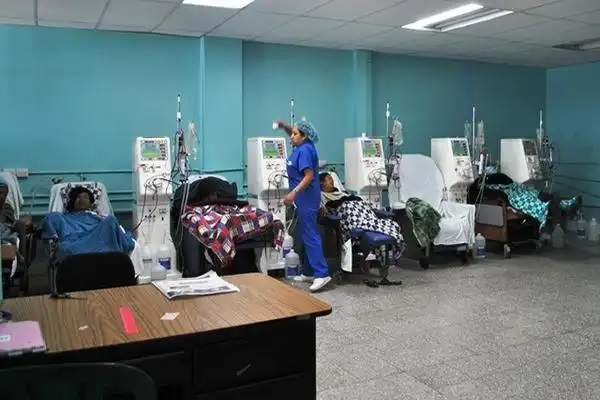 Fotografía de una sala de hospital con pacientes y una enfermera ayudando