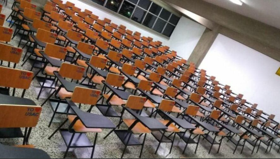 Fotografía de un salón de clases con escritorios vacíos